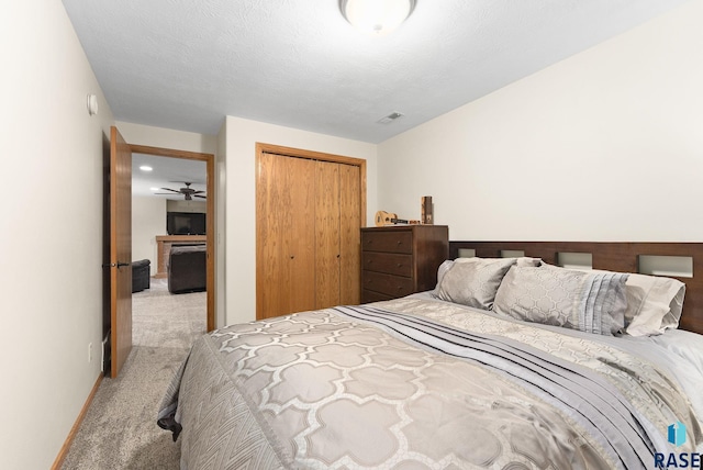 bedroom featuring light carpet, a textured ceiling, and a closet