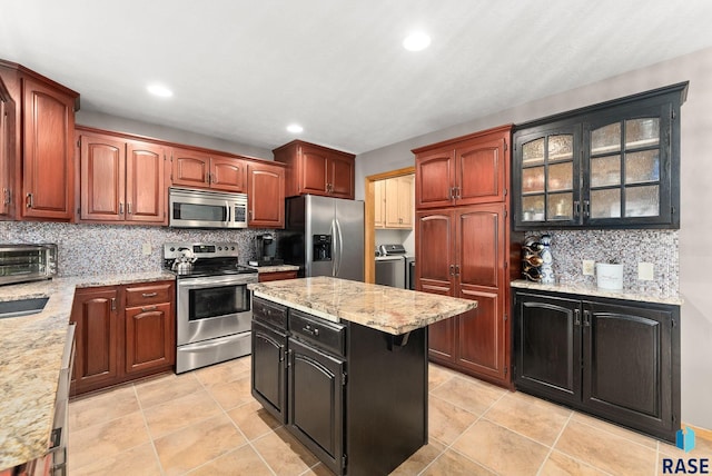 kitchen featuring light stone countertops, appliances with stainless steel finishes, washing machine and dryer, and backsplash