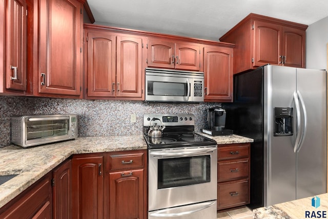 kitchen featuring light stone counters, stainless steel appliances, and backsplash