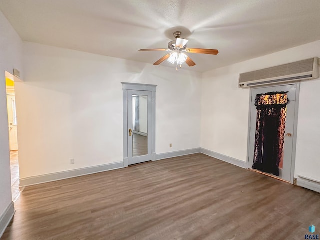 spare room featuring ceiling fan, an AC wall unit, and dark hardwood / wood-style floors