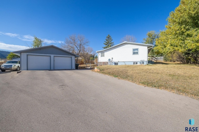 view of property exterior with a yard, a garage, and an outdoor structure