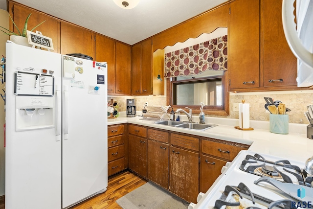 kitchen featuring white appliances, light hardwood / wood-style flooring, sink, and backsplash