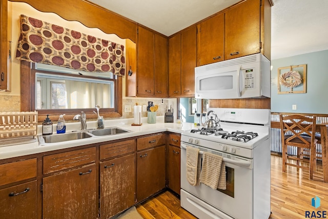 kitchen featuring backsplash, sink, light hardwood / wood-style floors, and white appliances