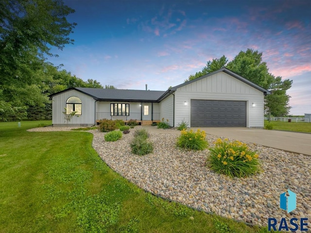 ranch-style home with covered porch, a garage, and a lawn