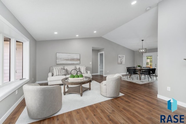 living room with lofted ceiling, hardwood / wood-style floors, and a notable chandelier