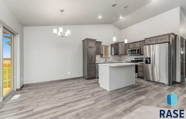 kitchen featuring a center island, dark brown cabinetry, decorative light fixtures, light wood-type flooring, and appliances with stainless steel finishes