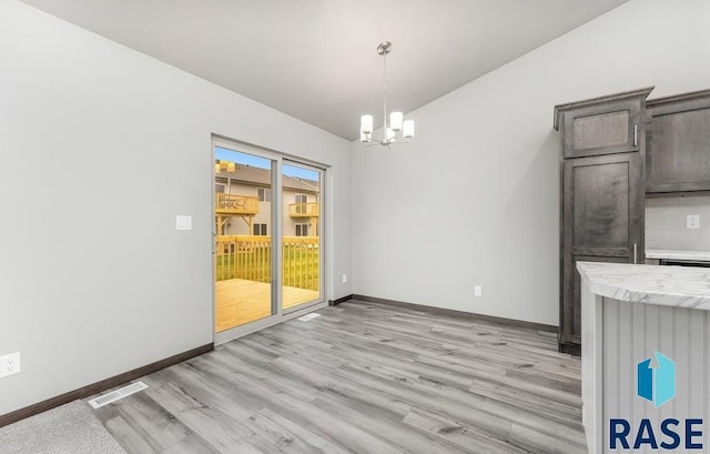 unfurnished dining area featuring light hardwood / wood-style flooring and a notable chandelier