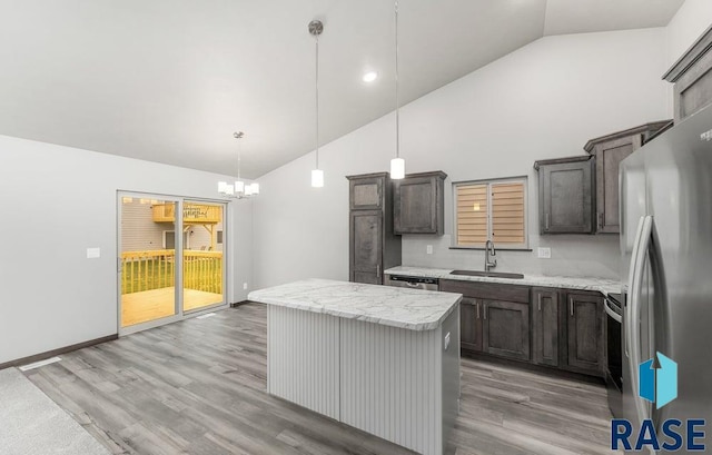 kitchen featuring a center island, hardwood / wood-style floors, stainless steel appliances, pendant lighting, and light stone counters