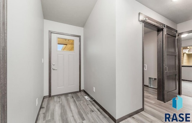 hall with light wood-type flooring and a barn door