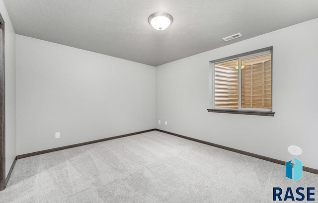 carpeted spare room featuring a textured ceiling