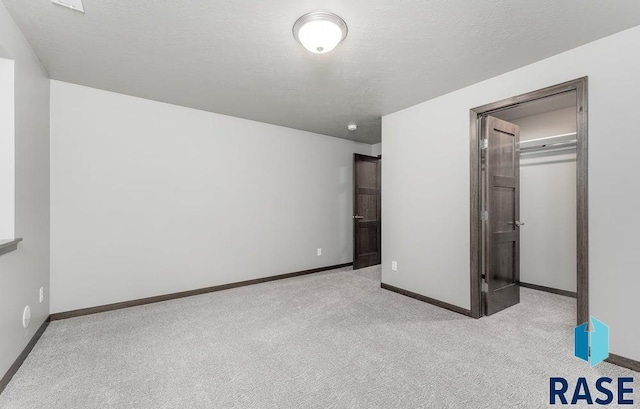 unfurnished bedroom with a closet, a textured ceiling, and light colored carpet