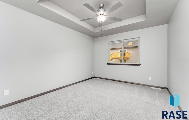 empty room featuring ceiling fan, carpet, and a raised ceiling