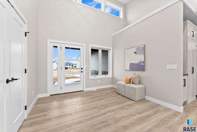 foyer entrance featuring a towering ceiling and light wood-type flooring