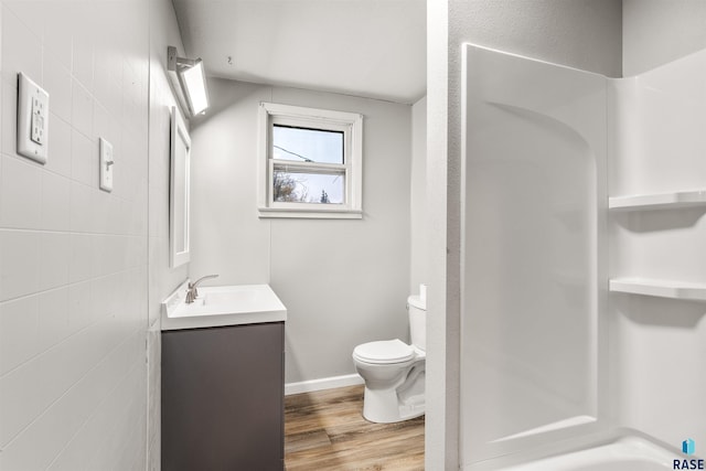 bathroom with tile walls, vanity, hardwood / wood-style floors, and toilet