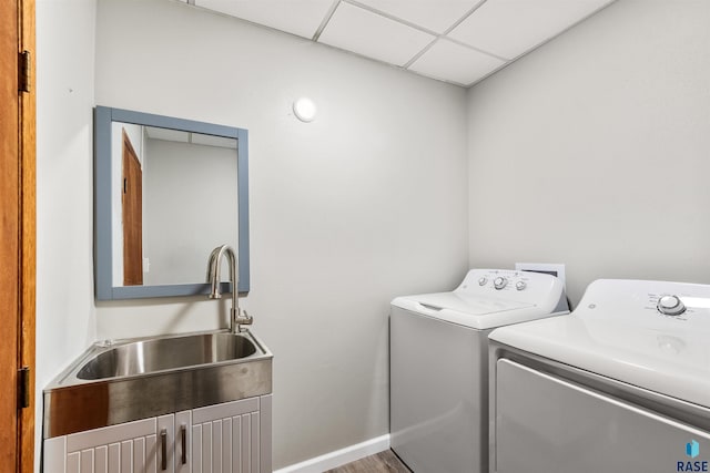 clothes washing area featuring sink, wood-type flooring, and washing machine and dryer