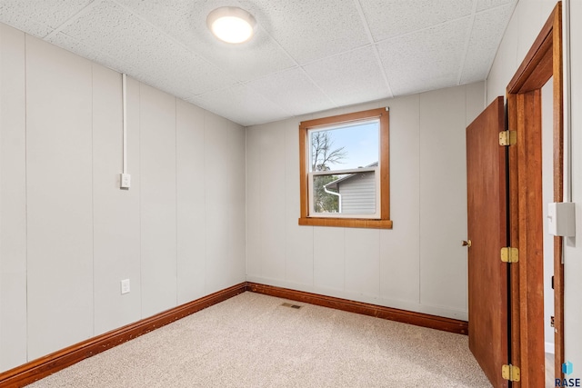 carpeted spare room featuring a drop ceiling