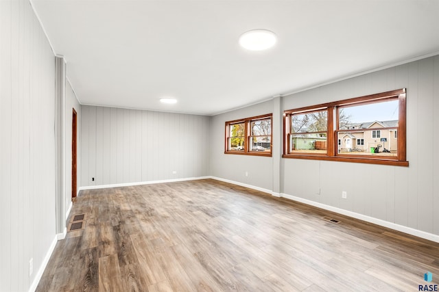 empty room with wood walls and light wood-type flooring