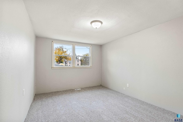 carpeted spare room with a textured ceiling