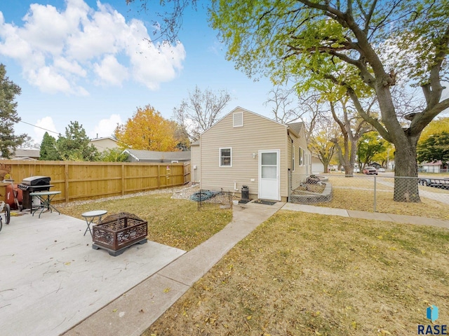 back of house featuring a patio area, a fire pit, and a yard