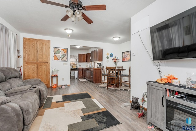 living room featuring light hardwood / wood-style floors, a textured ceiling, and ceiling fan