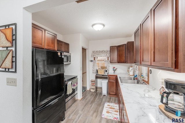 kitchen with light hardwood / wood-style floors, stainless steel appliances, a textured ceiling, and sink