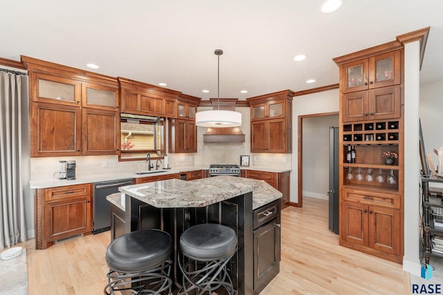 kitchen with appliances with stainless steel finishes, light wood-type flooring, a center island, hanging light fixtures, and a breakfast bar area