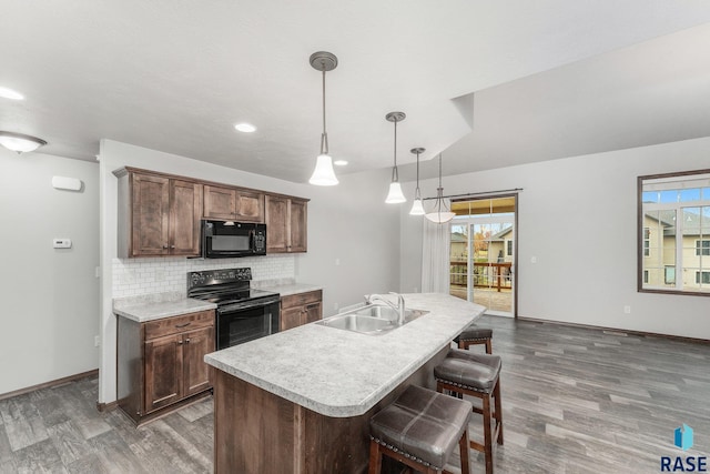 kitchen with dark wood-type flooring, black appliances, sink, and hanging light fixtures