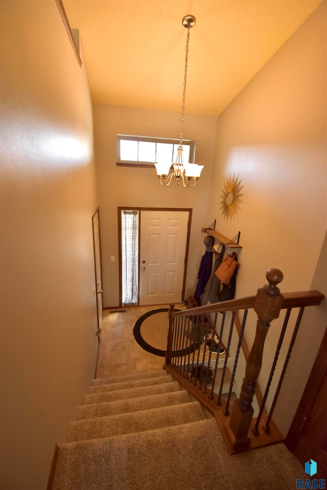 carpeted entryway featuring an inviting chandelier and high vaulted ceiling