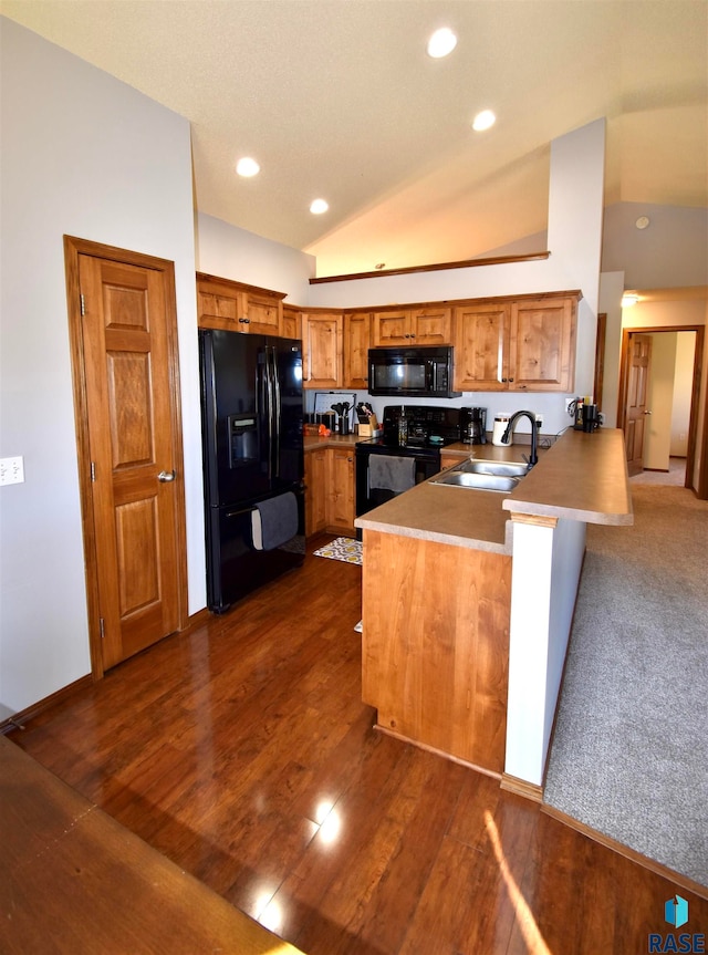 kitchen featuring black appliances, sink, kitchen peninsula, lofted ceiling, and dark wood-type flooring