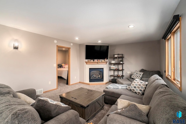 carpeted living room featuring a tiled fireplace