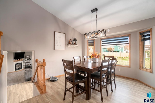 dining space featuring lofted ceiling, a notable chandelier, and light wood-type flooring