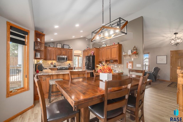 dining space featuring light hardwood / wood-style floors, vaulted ceiling, and a chandelier