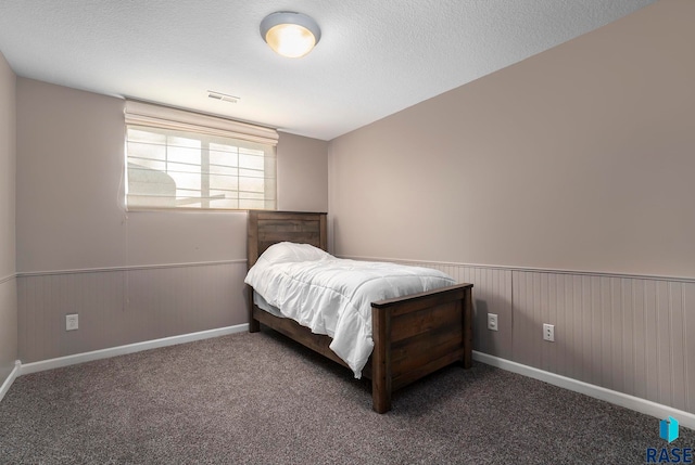 bedroom with a textured ceiling and dark colored carpet