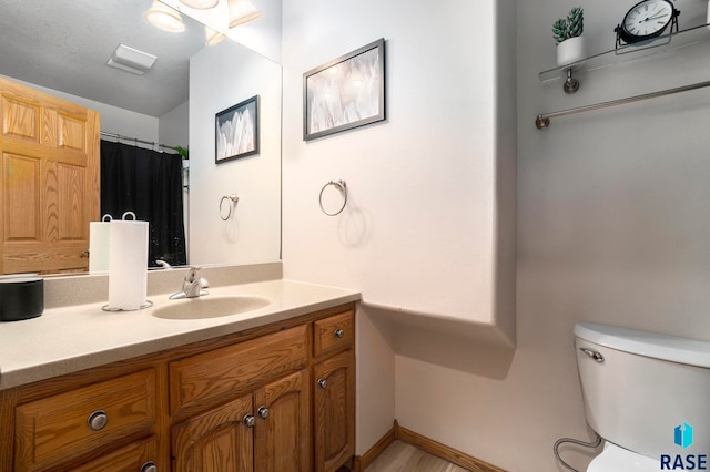 bathroom with vanity, toilet, and a textured ceiling