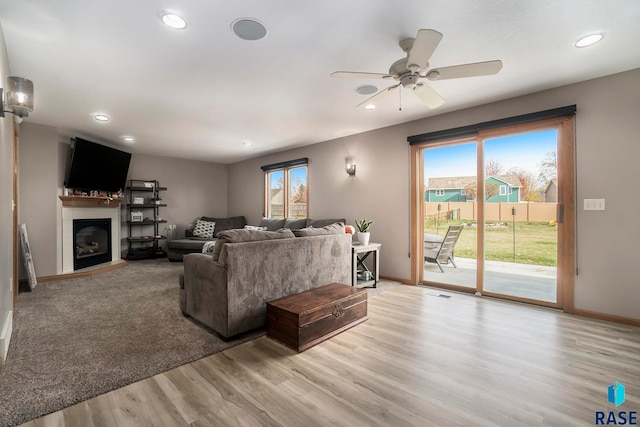 living room featuring ceiling fan, light wood-type flooring, and a wealth of natural light