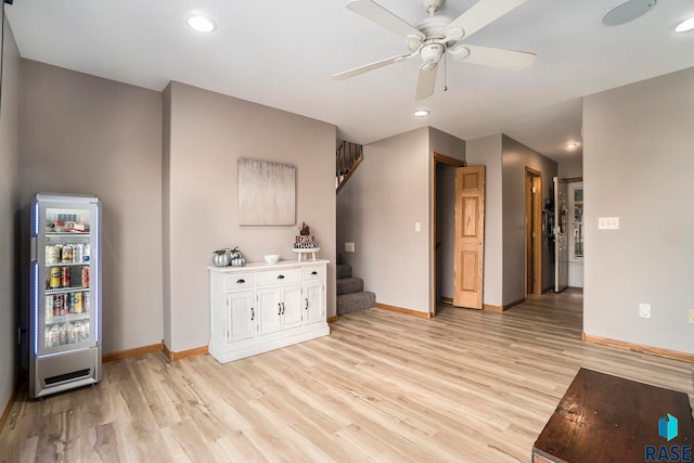 unfurnished living room with beverage cooler, light wood-type flooring, and ceiling fan