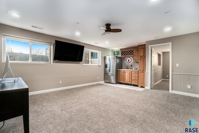 unfurnished living room with light carpet, sink, and ceiling fan