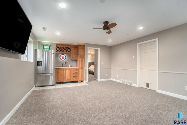 unfurnished living room featuring light carpet, wet bar, and ceiling fan