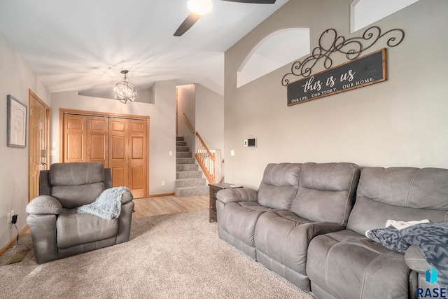 living room featuring carpet, vaulted ceiling, and ceiling fan with notable chandelier