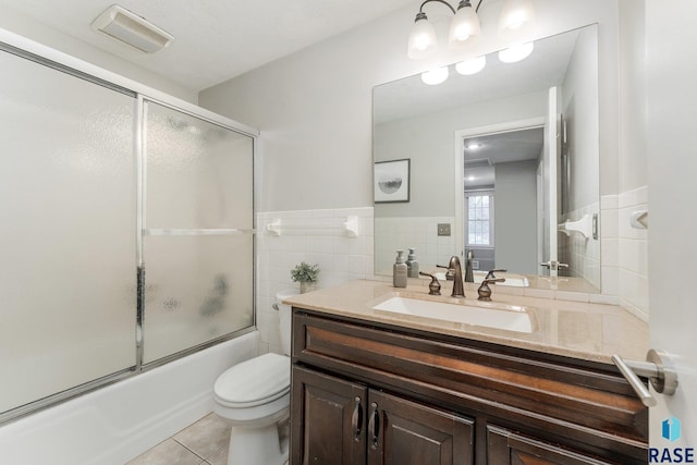 full bathroom featuring toilet, tile walls, tile patterned flooring, bath / shower combo with glass door, and vanity