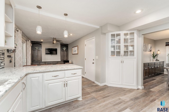 kitchen with white cabinets, pendant lighting, and light wood-type flooring