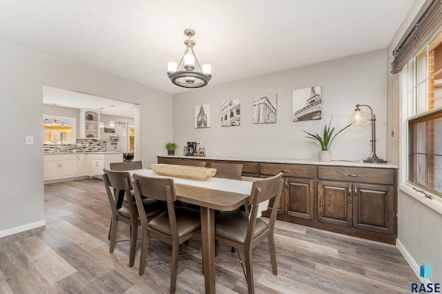 dining room featuring light wood-type flooring, a textured ceiling, sink, and an inviting chandelier