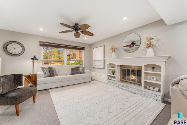 carpeted living room with ceiling fan and a fireplace