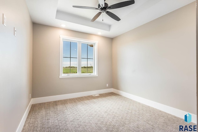 spare room with carpet, ceiling fan, and a raised ceiling