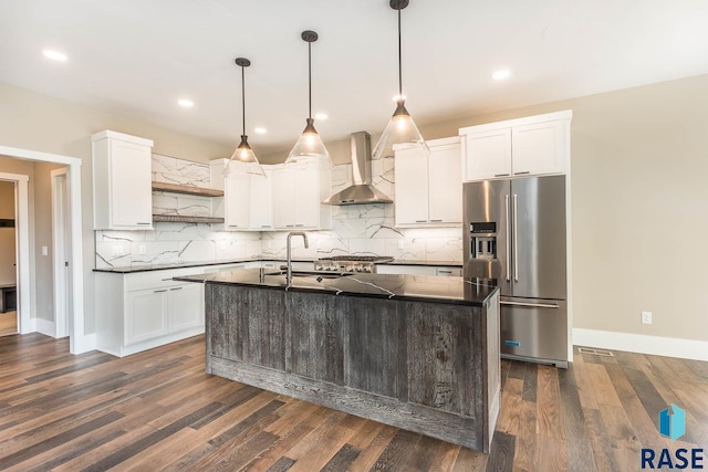 kitchen featuring sink, wall chimney range hood, dark hardwood / wood-style floors, high quality fridge, and a kitchen island with sink