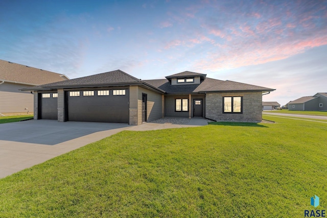 prairie-style house featuring a garage and a lawn