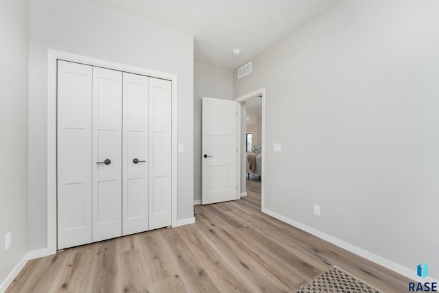 unfurnished bedroom featuring light hardwood / wood-style flooring and a closet