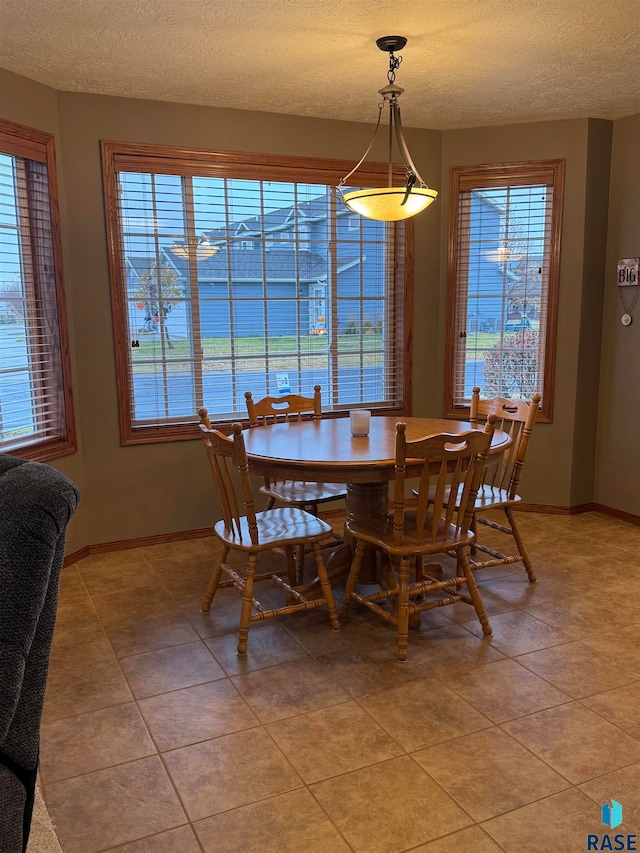 dining room with a wealth of natural light, light tile patterned floors, and a textured ceiling