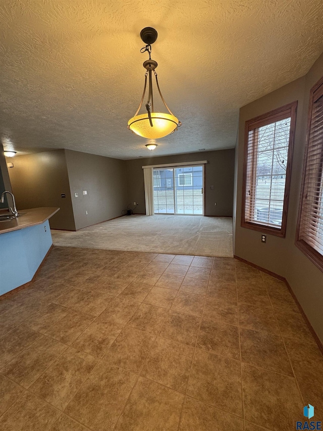 unfurnished dining area with sink, carpet floors, and a textured ceiling