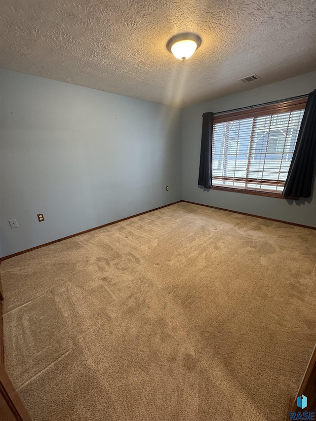 carpeted empty room with a textured ceiling